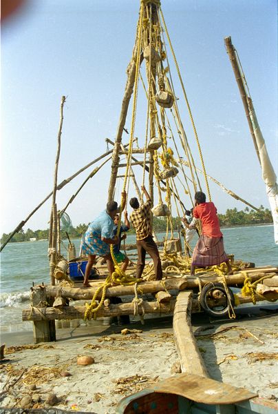 Filets chinois. Les pêcheurs relèvent le filet en descendant le mat servant de levier. Des pierres servent de contre-poids