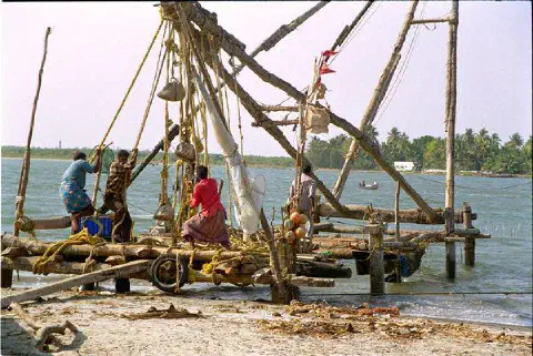 Filets chinois. Les pêcheurs relèvent le filet en descendant le mat servant de levier. Des pierres servent de contre-poids